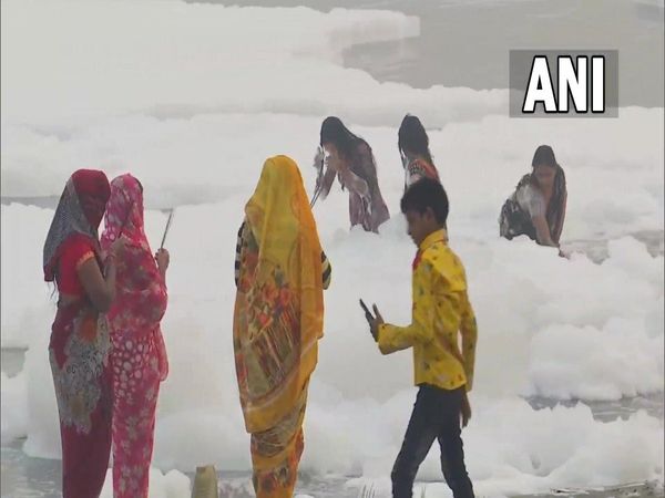 People take dip in Yamuna river near Kalindi Kunj in Delhi on the first day of Chhath Puja in the midst of toxic foam