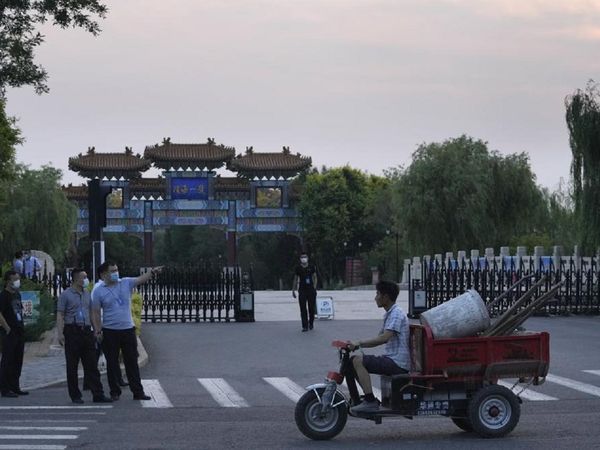 चीन के तियानजिन में सामान लेकर जा रहा एक कामगार और चेक पोस्‍ट पर खड़े सुरक्षाकर्मी